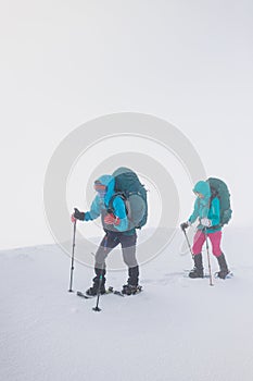 climbers climb the mountain. Winter mountaineering. two girls in snowshoes walk through the snow
