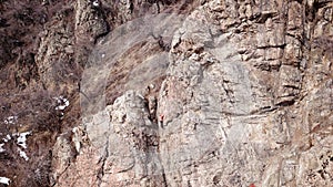 Climbers climb the rock. Drone footage. Side and top view. Rock lesson in the highlands. Gray rocks and dry bushes. Sometimes ther