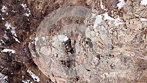 Climbers climb the rock. Drone footage. Side and top view. Rock lesson in the highlands. Gray rocks and dry bushes. Sometimes ther