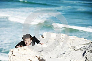 Climbing cliff, frustrated or businessman with stress for job, career opportunity or work crisis at beach. Professional