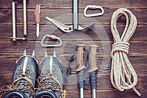 Climbing equipment: rope, trekking shoes, crampons, ice tools, ice ax, ice screws, red knife and other set on dark wooden