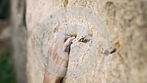 Climbing moments. extreme closeup woman`s hand reaching and holding rock holds on a yellow cliff