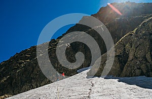 Climbing team roping up woman and man dressed high altitude mountaineering clothes with backpacks walking by snowy slope in the