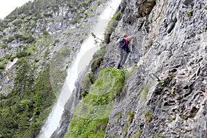 Climbing woman is near a waterfall