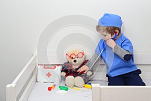 Clinic. Adorable child dressed as doctor playing with toy. Health exam by young medical worker. Educative and