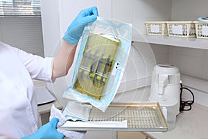 A clinic employee holds sterile instruments in a craft sealed bag. The concept of sterility and hygiene in clinics. An