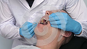 In the clinic hospital The doctor doctor`s assistant checks the patient`s teeth for the treatment of tartar and plaque, dental