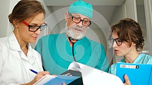 Clinic medical staff at work. Doctor surgeon and two of his medical assistant young women. Close portrait, medicine and