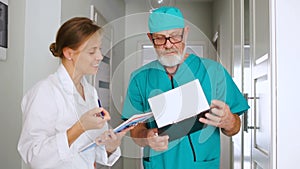 Clinic medical staff at work. A young female doctor and her mature colleague discuss a medical history and treatment