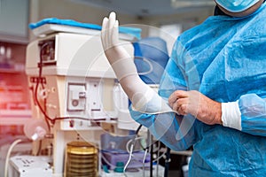 Clinic worker wearing a surgical gloves against infection. Professional handsome medical specialist in mask.