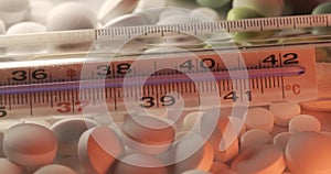 Clinical thermometer on different medical pills and medicine. Panning from lower temperature to higher temperatures. Fever