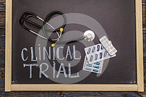 Clinical trial concept. Chalk board, stethoscope, pills