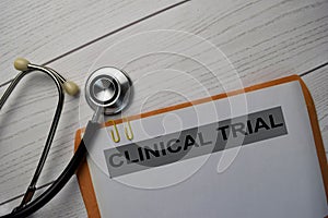 Clinical Trial text with document brown envelope and stethoscope isolated on office desk