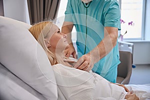 Clinician performing cardiac auscultation of hospitalized woman