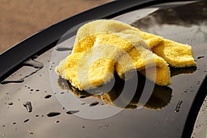 Clining car. Wiping panel of a luxury car with yellow microfiber, close-up view photo