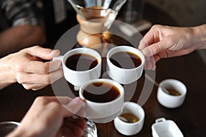 Clink glasses with three cups of coffee on the background of coffee items at the tasting