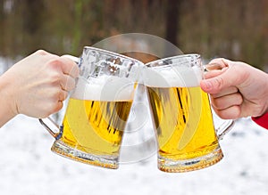 Clinking Beer glasses on winter forest background.