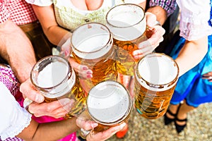 Clinking glasses with beer in Bavarian beer garden