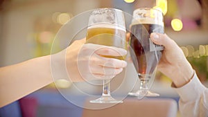 Clinking glasses with dark and light beer in bar