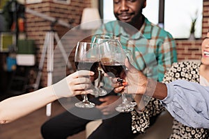 Clinking glasses of red wine at apartment party