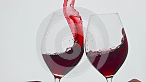 Clinking raising red beverage vessels closeup. Rose wine splashing over the edge
