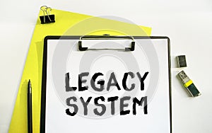 A clip-on folder labeled LEGACY SYSTEM. Top view of a desktop along with documents, charts and business accessories. Finance or