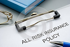 Clipboard with all risk insurance policy and pen.