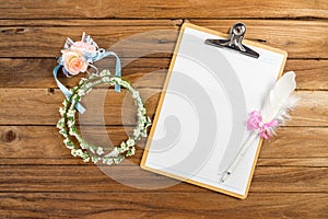 Clipboard attach planning paper with pen beside rose headband