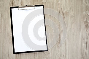 Clipboard with a blank sheet of paper on wooden table.