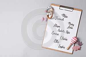 Clipboard with different baby names and toys on grey background, top view. Space for text photo