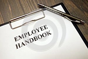 Clipboard with employee handbook and pen on desk photo