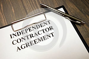 Clipboard with independent contractor agreement and pen on desk