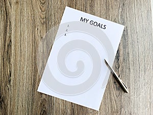 Clipboard with my goals on wood desk.