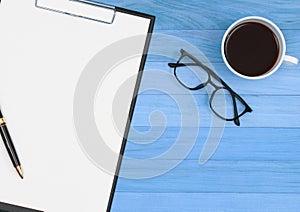 Clipboard with pen ,eyeglasses and coffee cup on vintage blue wood background, template, mock up, flat lay, top view