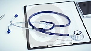 Clipboard, pen, smartphone and medical stethoscope lying on the table in clinical office.