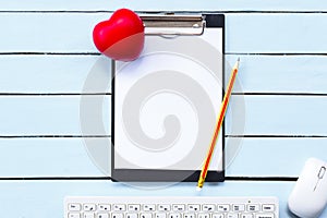 Clipboard and red heart with pencil and keyboard on blue wooden table.Health concept.