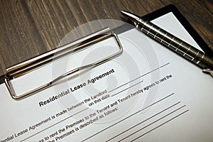 Clipboard with residential lease agreement and pen on desk
