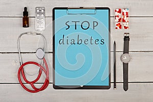 clipboard with text & x22;STOP diabetes& x22;, stethoscope, pills, watch