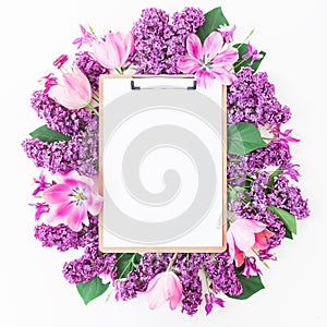 Clipboard, tulips and lilac branch on pink background. Flat lay, top view. Beauty blog concept.