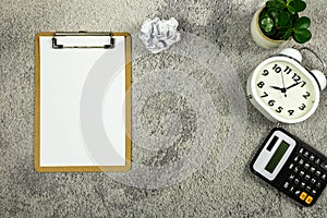 Clipboard and white paper, alarm clock, calculator, white paper ball and pencil on the desk