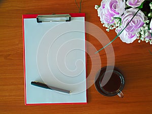 Clipboard with white sheet and black pen and a cup of hot coffee