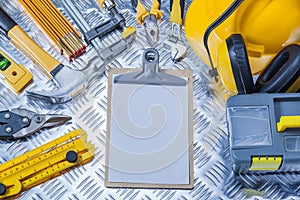 Clipboard with white sheet of paper and set construction tools