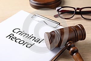 Clipboard with words CRIMINAL RECORD and gavel on table, closeup
