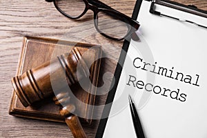Clipboard with words CRIMINAL RECORD and gavel on table, flat lay