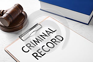 Clipboard with words CRIMINAL RECORD and gavel on white table, closeup