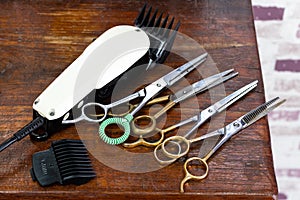 Clippers and many scissors placed on the wooden table