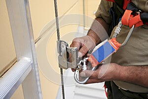 Clipping industrial Karabiner connected with fall arrest shock absorbing safety lanyard device into vertical lifeline photo