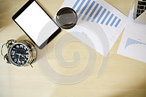 Clipping path Office desk background with blank tablet, clock, report paper, notebook laptop and cup of coffee. View from above