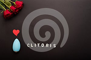 Clitoral vibrator, heart and a bouquet of scarlet roses on a black background. Copy space.