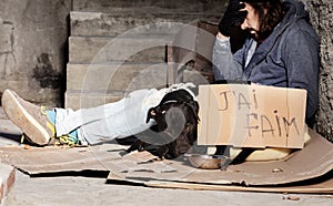 Clochard sitting with his dog on backstreet yard